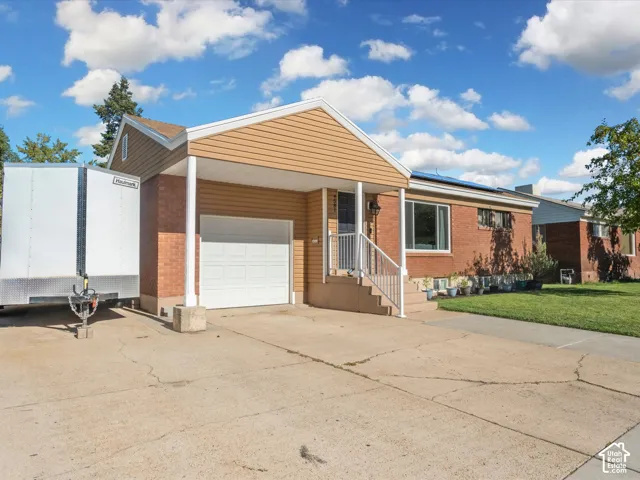 Exterior featuring brick and horizontal siding, a covered entryway with white railings, an attached garage, and a concrete driveway