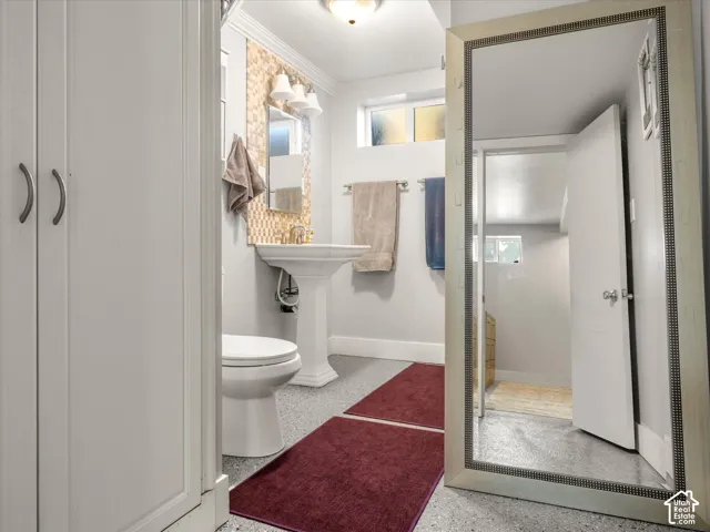 Pedestal sink with a decorative tiled backsplash and wall-mounted light fixture