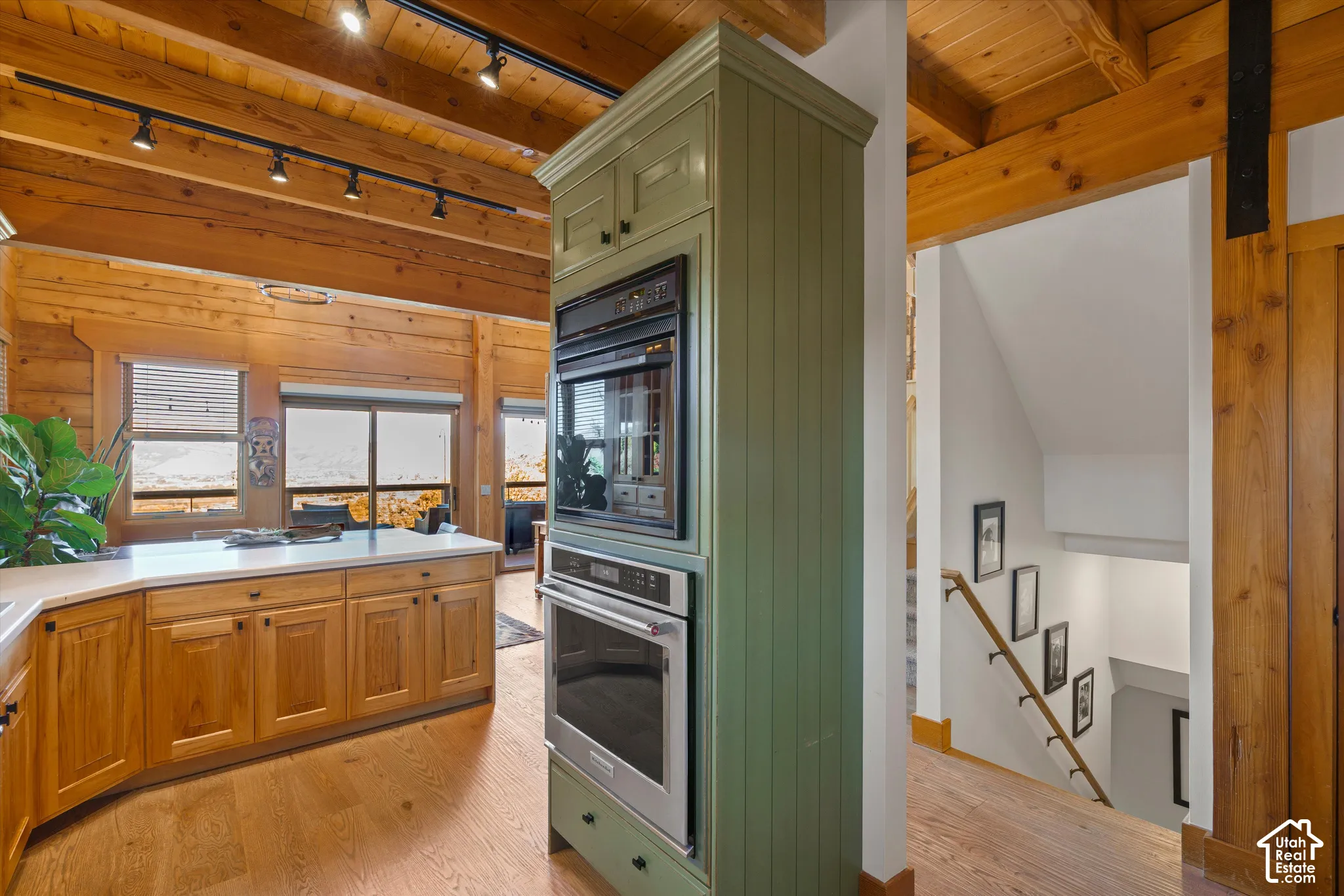 Built-in stainless steel appliances, wood-finish flooring, exposed wood beam ceiling, white countertops, and wood cabinetry