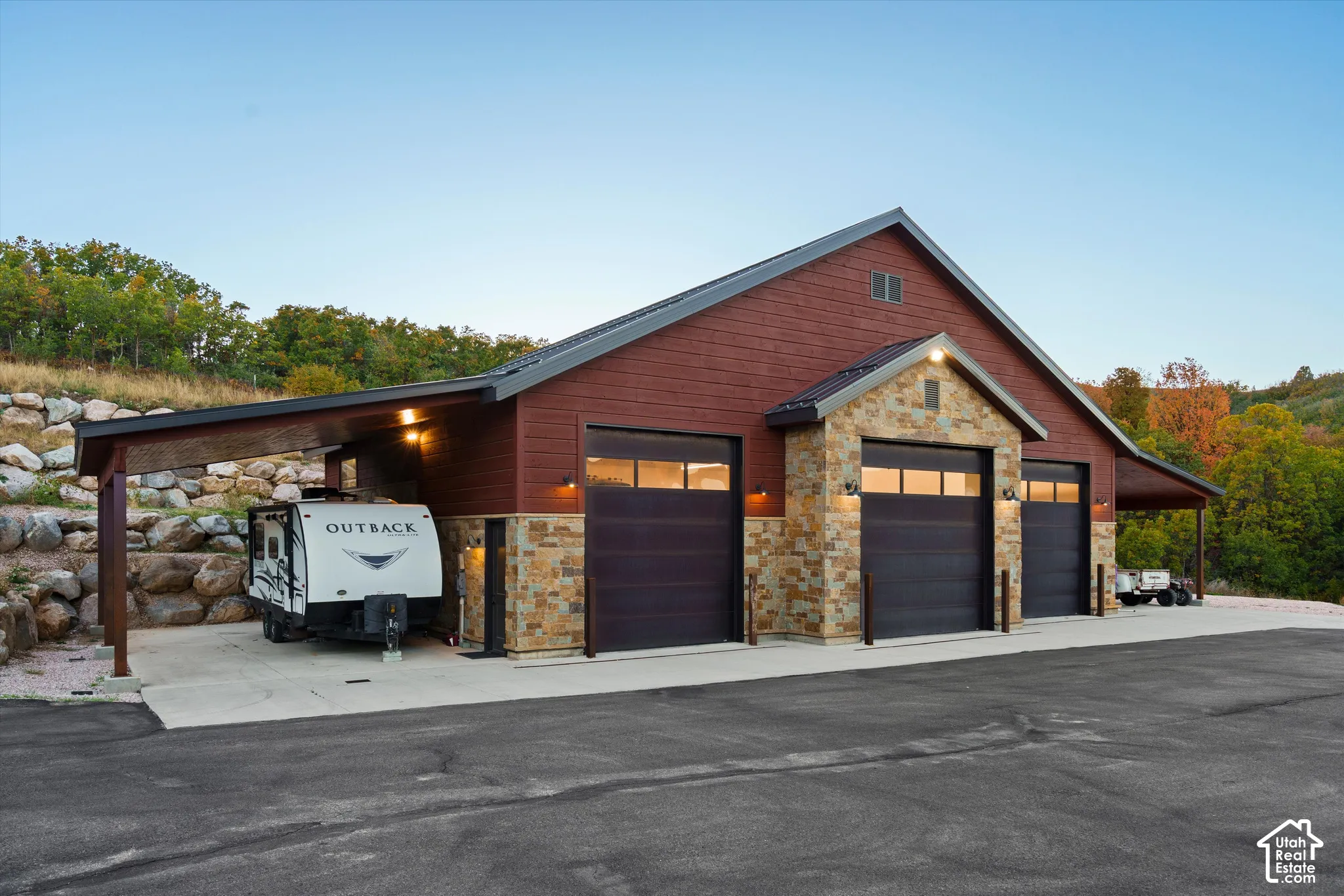 Expansive garage structure featuring multiple overhead doors, stone accents, a covered parking area, and a durable asphalt driveway
