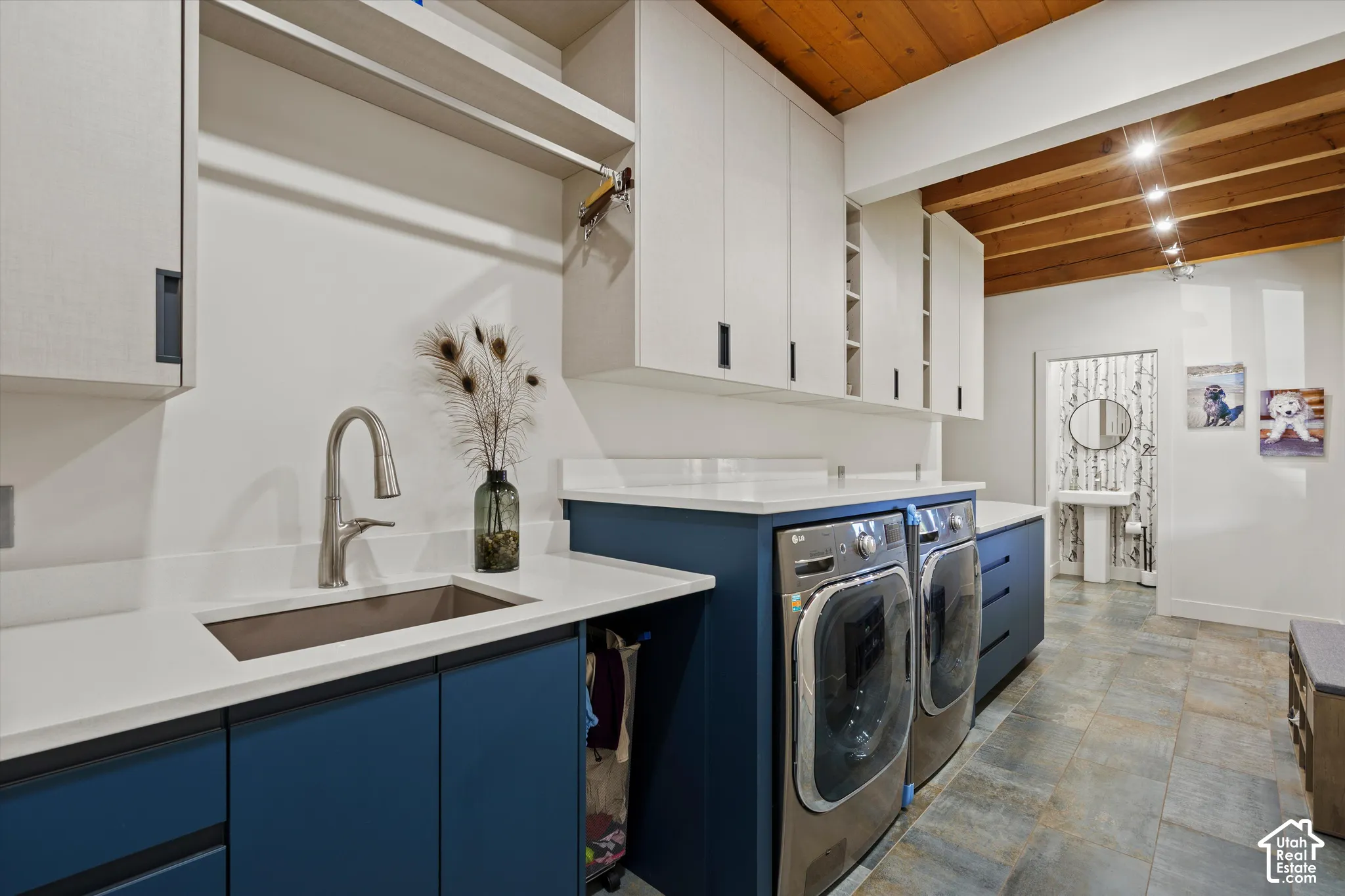 Wood-finish ceiling with exposed beams, white upper cabinetry, white countertops, built-in stainless steel appliances, and blue lower cabinetry