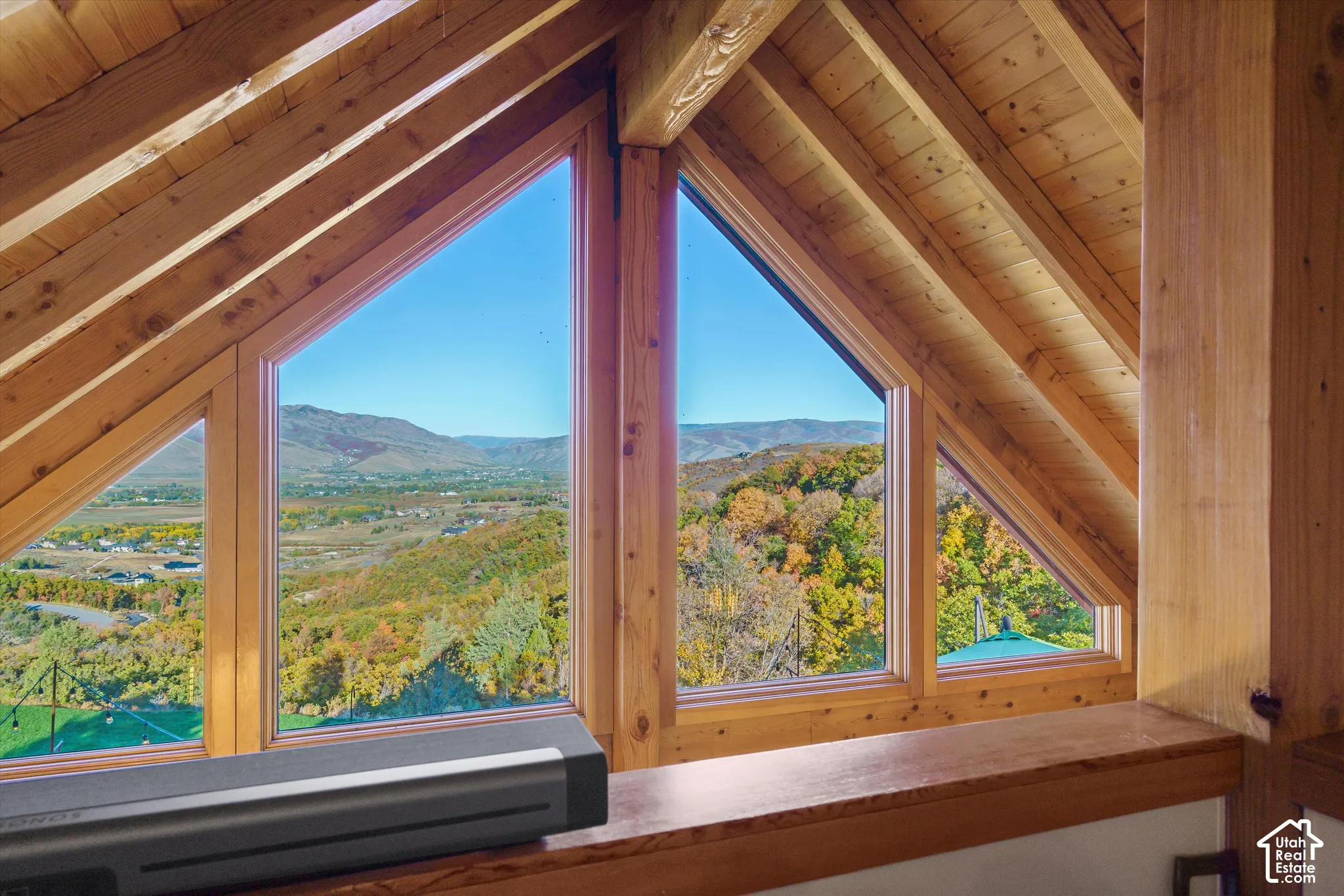 Exposed wood beams and ceiling with multiple triangular windows framing a mountainous landscape