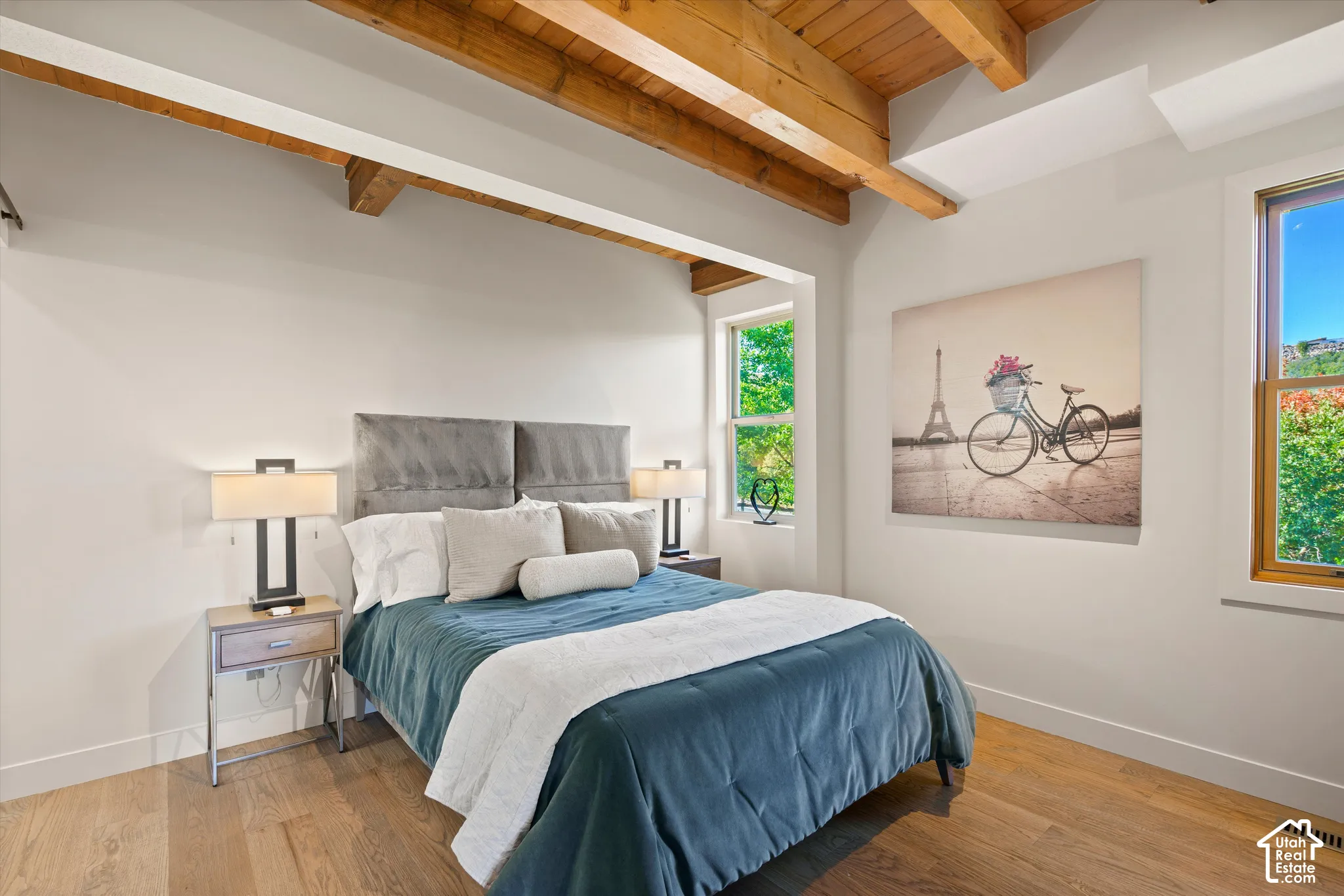Exposed wood beam ceiling, natural wood-finish flooring, recessed windows, and modern wall sconces