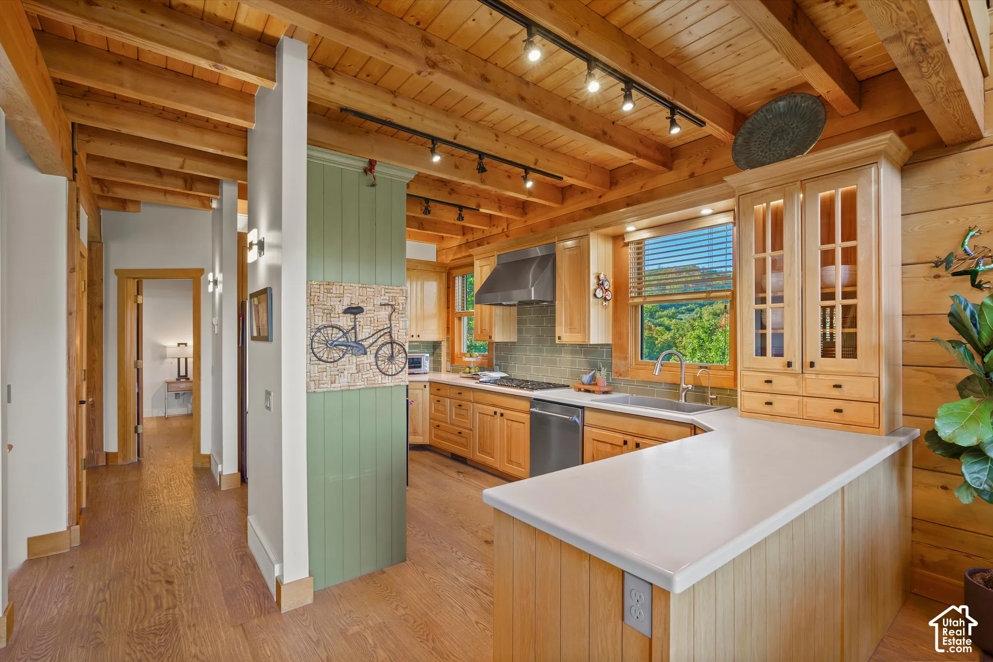 Kitchen featuring wood-finish cabinetry, stainless steel appliances, a tile backsplash, and light-toned countertops