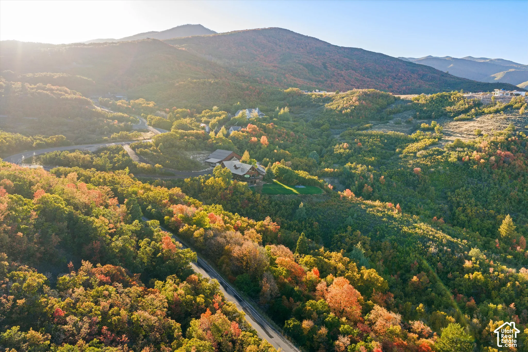 Expansive mountainous terrain with varied foliage and a paved roadway