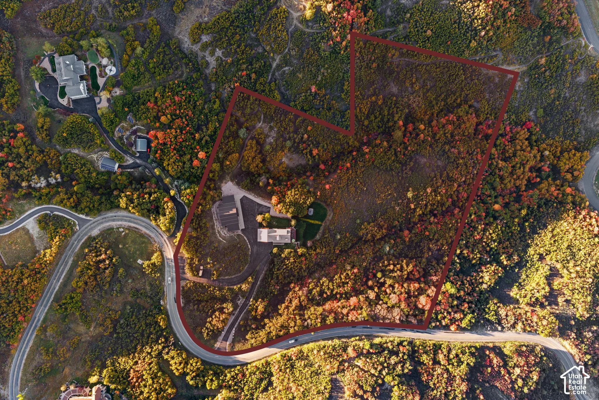 Expansive natural terrain surrounding a curved roadway, featuring a structured lot outline and established residences