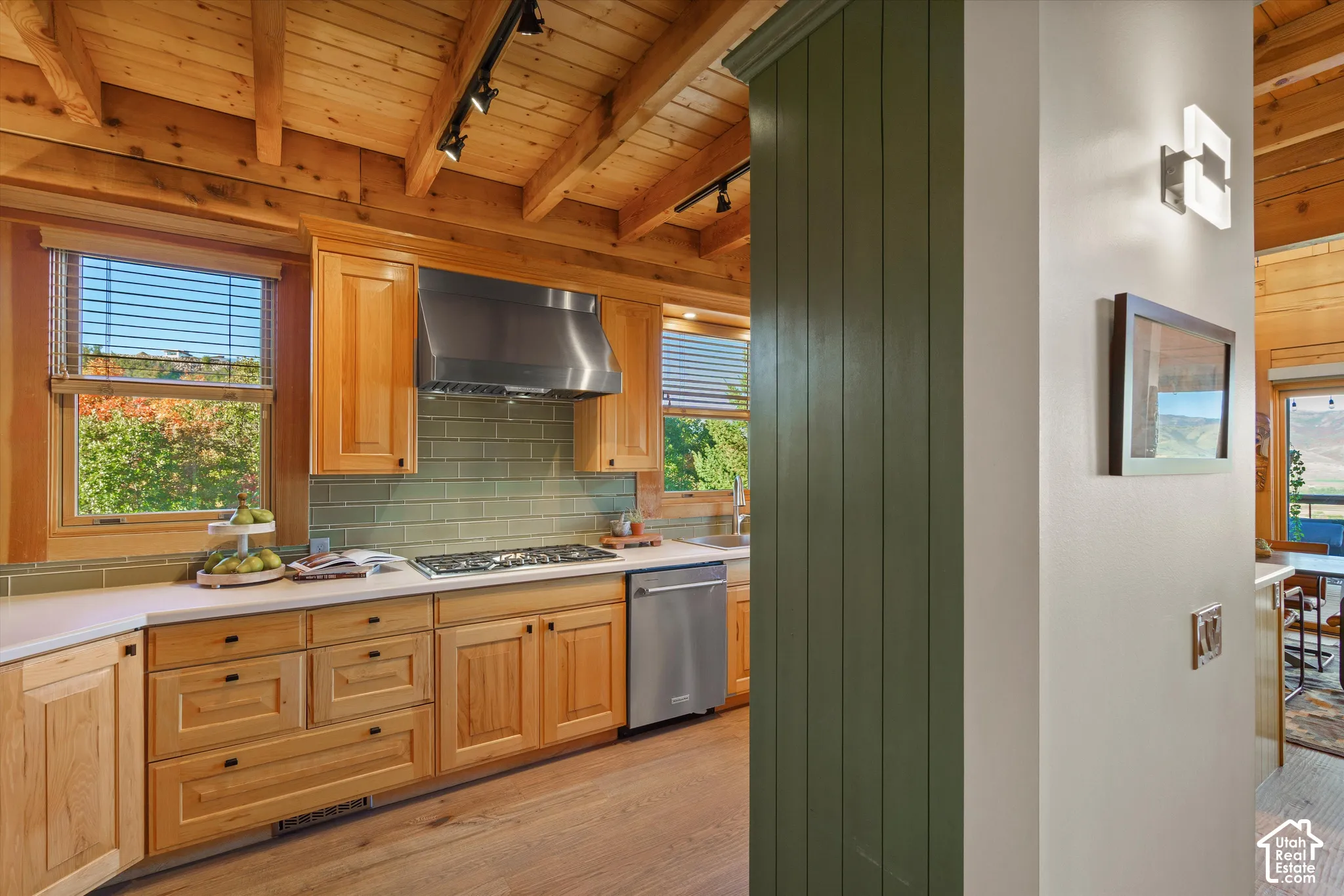 Kitchen featuring wood cabinetry, stainless steel appliances, a tile backsplash, and wood-finish flooring