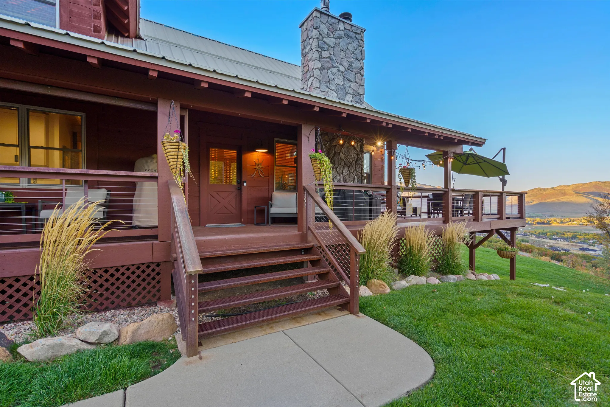 Expansive exterior deck with metal cable railings, a stone chimney, and a metal roof