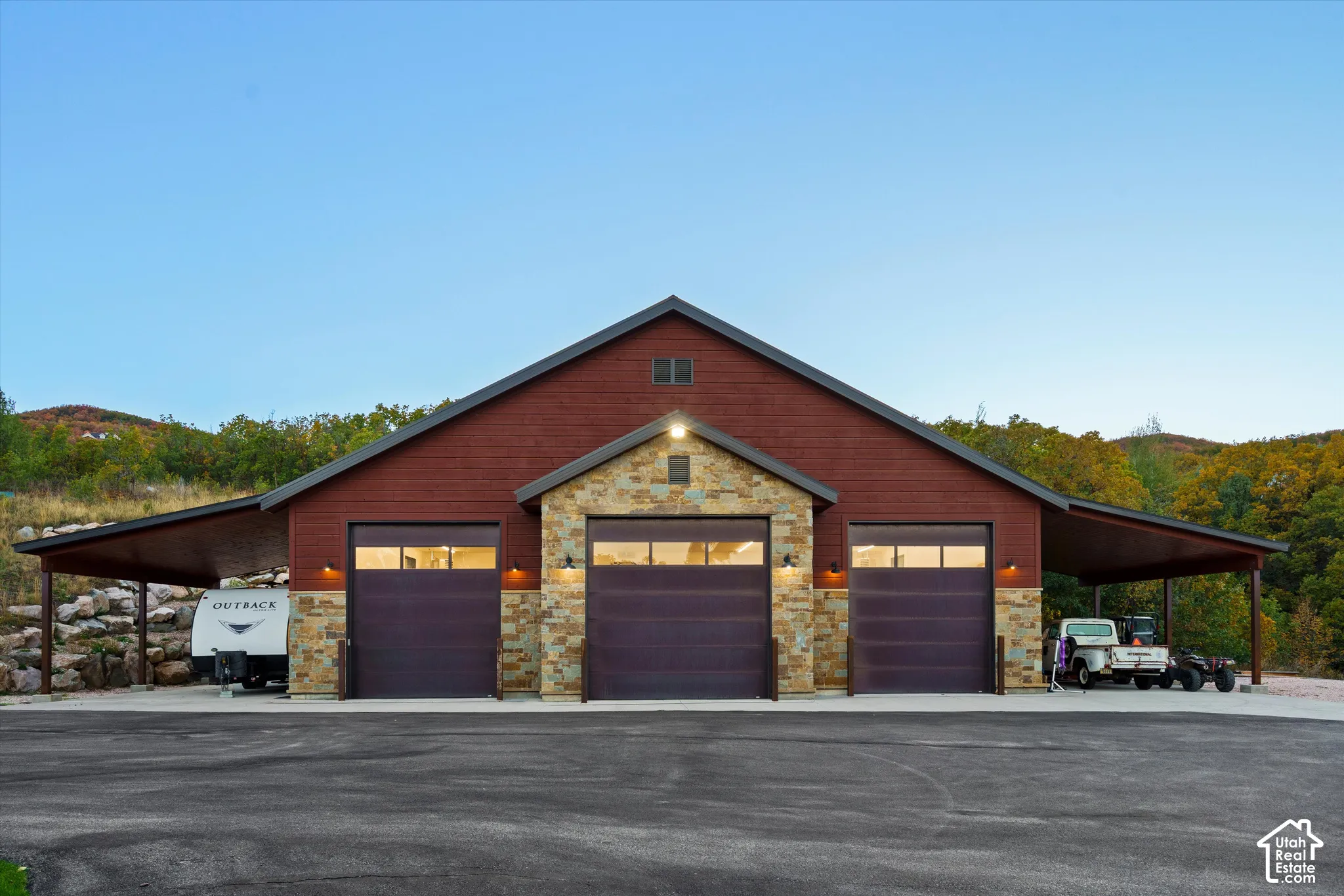 Three-bay garage building with a stone facade, wood siding, and covered side awnings