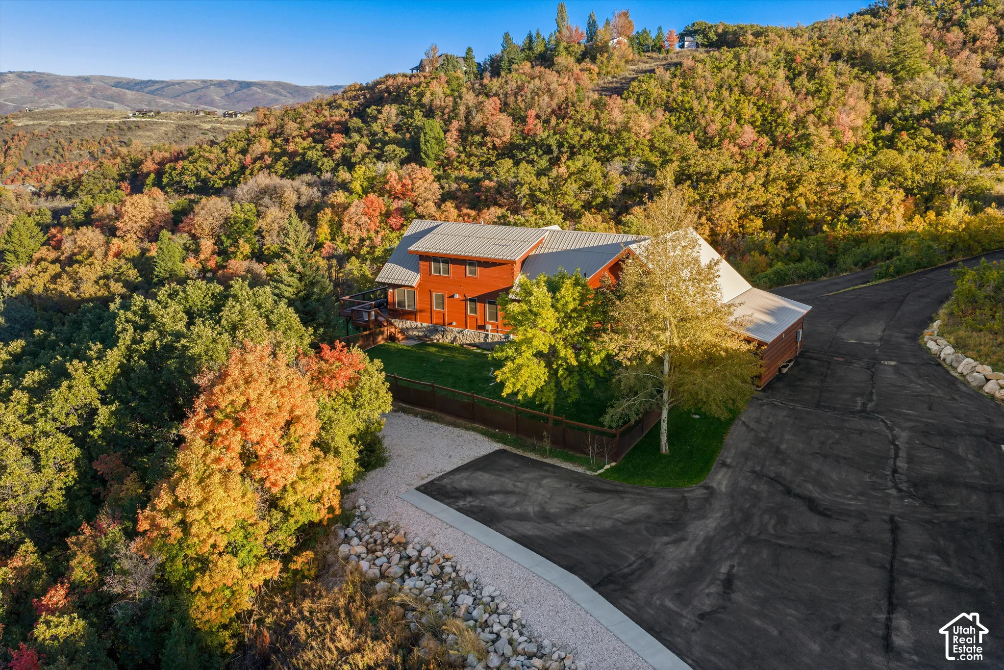 Red-sided residence with a gray metal roof, surrounded by mature trees