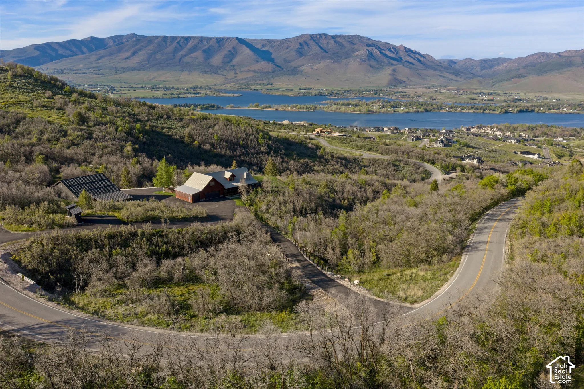 Expansive mountain and lake scenery with a winding paved road leading to the property