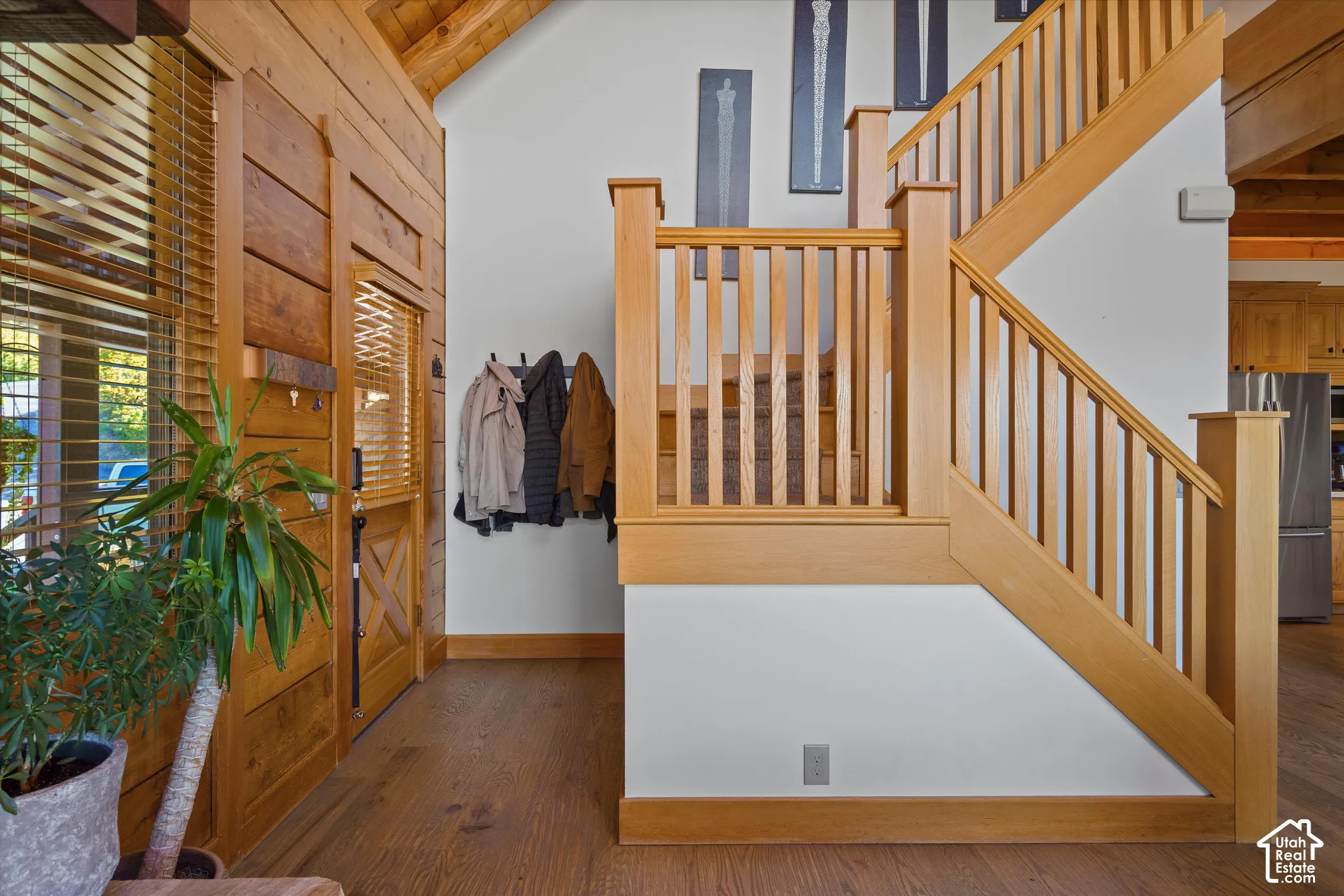 Solid wood flooring, natural wood wall paneling, natural wood door with X-detail, and a custom wood staircase with balusters