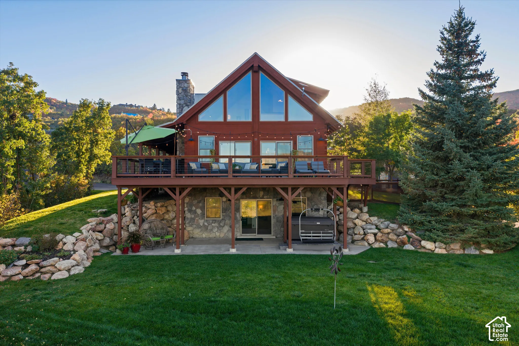 Gable-style home featuring a stone foundation, prominent deck, and a stone chimney