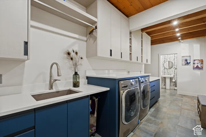 Wood-finish ceiling with exposed beams, white upper cabinetry, white countertops, built-in stainless steel appliances, and blue lower cabinetry
