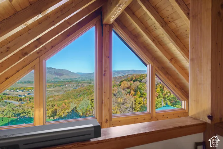 Exposed wood beams and ceiling with multiple triangular windows framing a mountainous landscape