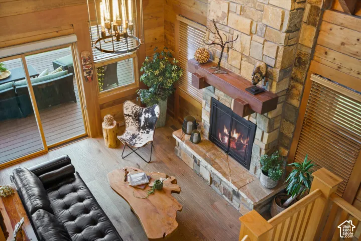 Stone fireplace with wood mantel, wood-finish flooring, wood plank walls, and a sliding glass door to an outdoor deck