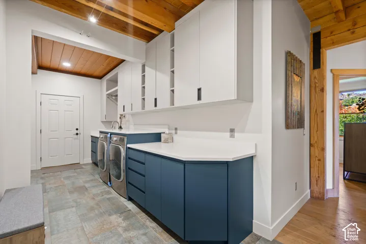 Exposed wood beam ceiling, white upper cabinetry, blue lower cabinetry, white countertops, and tile flooring
