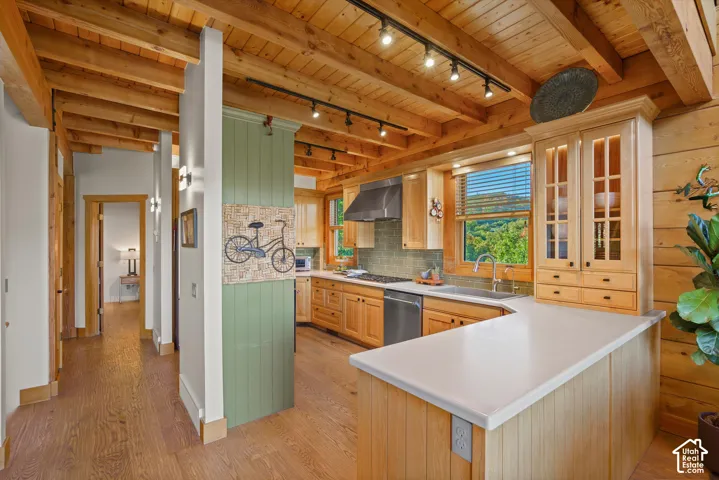 Kitchen featuring wood-finish cabinetry, stainless steel appliances, a tile backsplash, and light-toned countertops