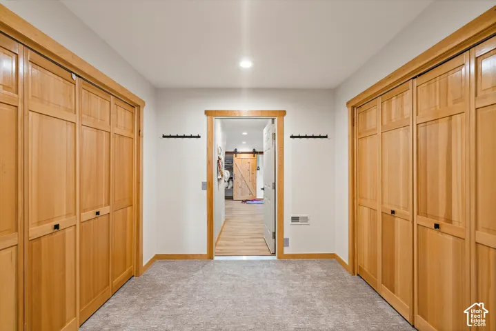 Recessed lighting illuminates the hallway with light wood-finish trim, panel doors, and gray carpeting