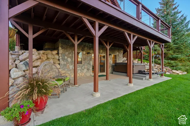 Covered patio with a concrete surface, stone facade, and integrated hot tub area