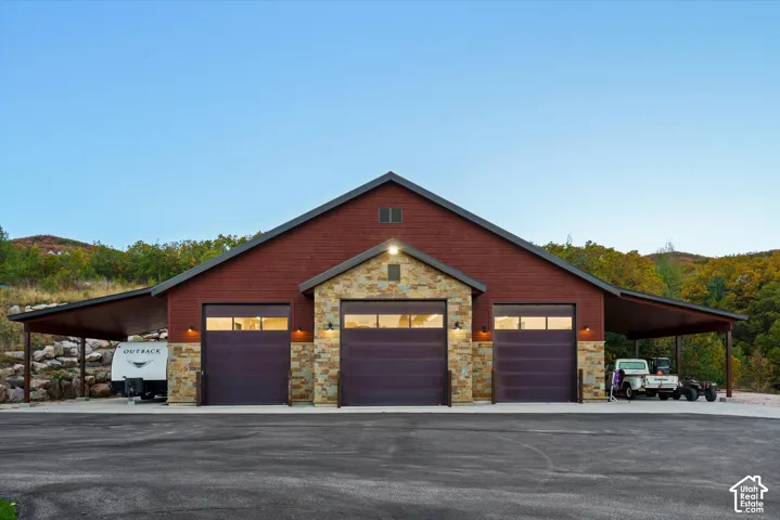 Three-bay garage building with a stone facade, wood siding, and covered side awnings