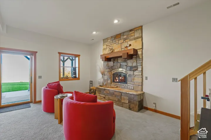 Stone-faced fireplace with a wood mantel, wood-framed windows, and a sliding glass door