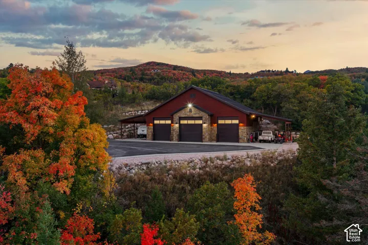 Structure with three dark garage doors, stone facade accents, and a red siding exterior