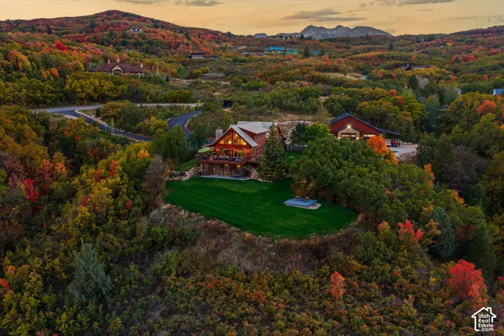 Log cabin architecture with multiple decks, expansive manicured lawn, and detached garage