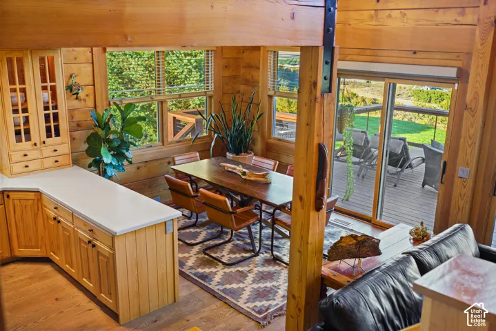 Open-concept living space with exposed wood beams, wood-finish flooring, and a kitchen island with light countertops