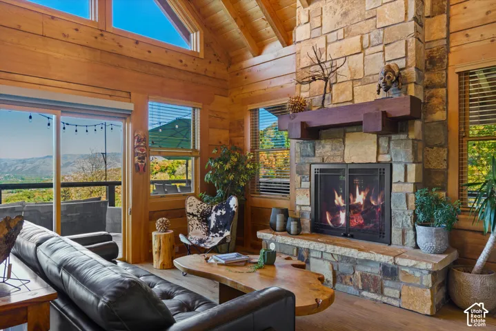 Stone-clad fireplace with wood mantel, vaulted wood-paneled ceilings, wood-finish flooring, and expansive glass sliding doors