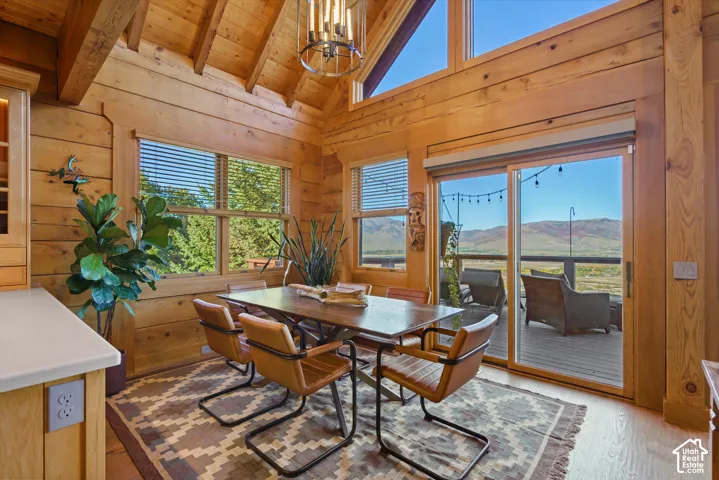 Vaulted wood-paneled ceilings with exposed beams, wood-plank walls, and a contemporary chandelier
