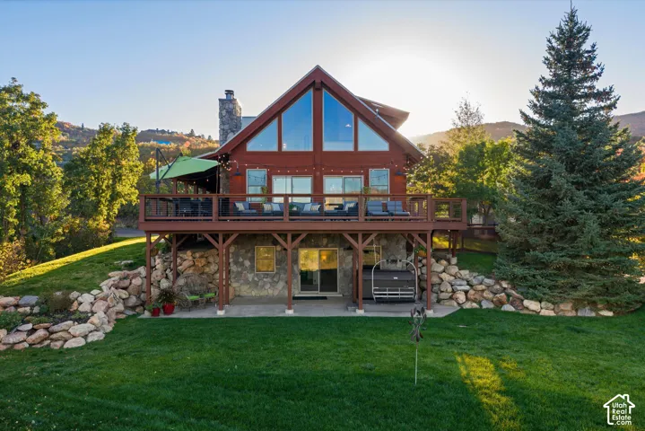 Gable-style home featuring a stone foundation, prominent deck, and a stone chimney