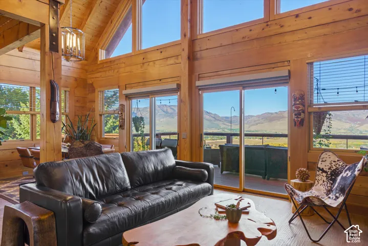 Vaulted wood-paneled ceilings with exposed beams, expansive windows, and a sliding glass door providing access to an outdoor area