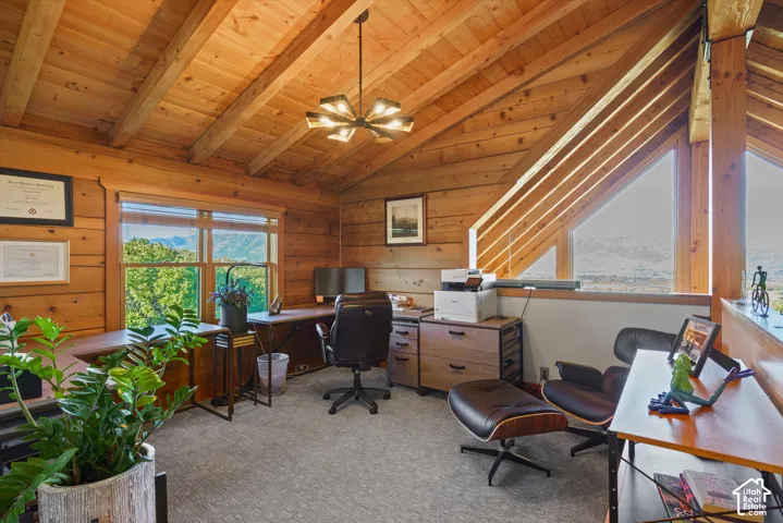 Wood-paneled walls and ceiling with exposed beams, large windows, and a multi-level ceiling design