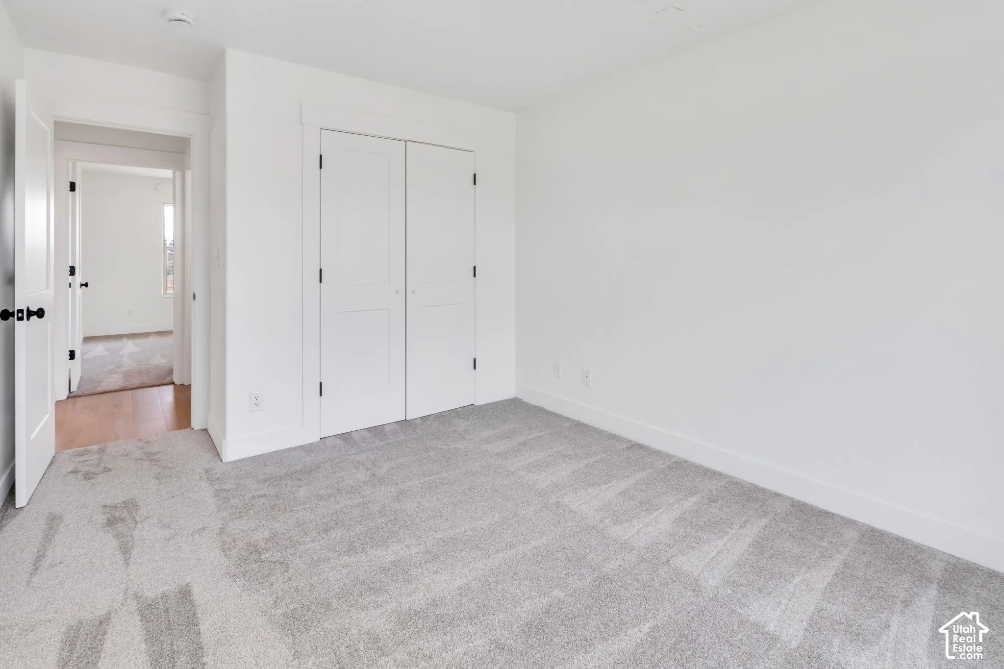 White walls, light gray carpet, and white bi-fold closet doors