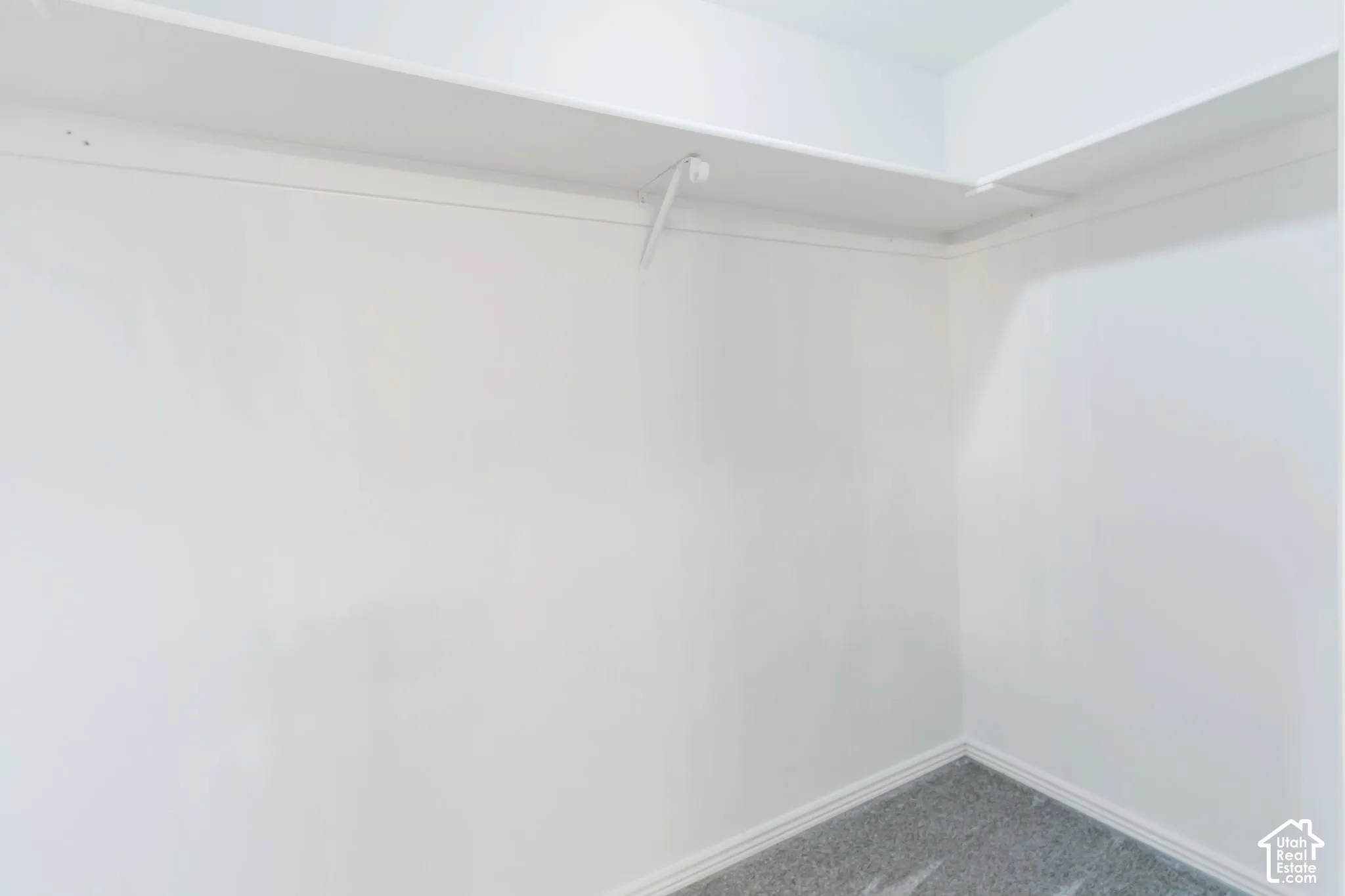 White wall finishes, upper shelving, and a hanging rod