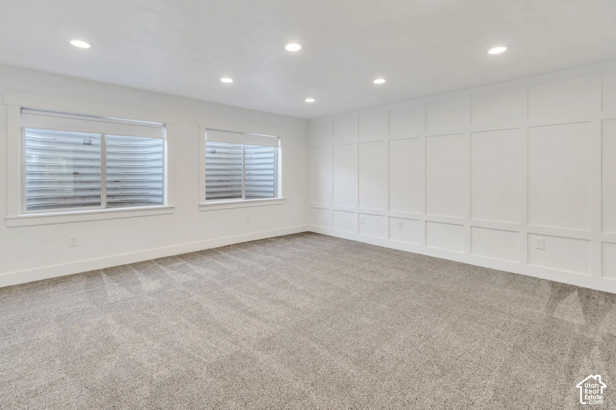 Recessed lighting, light gray carpet, window treatments, white wainscoting, and white trim