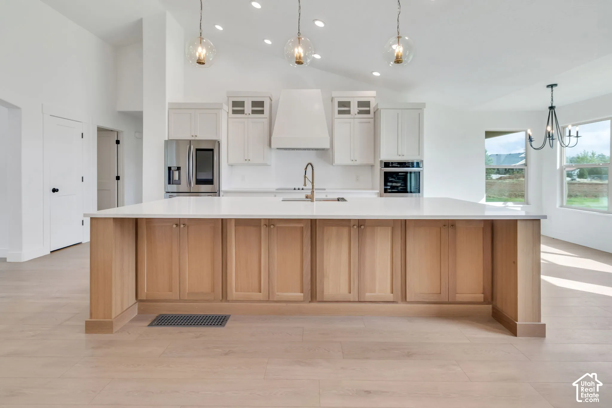 Spacious kitchen featuring a large island with wood-finish cabinetry, stainless steel appliances, and vaulted ceilings
