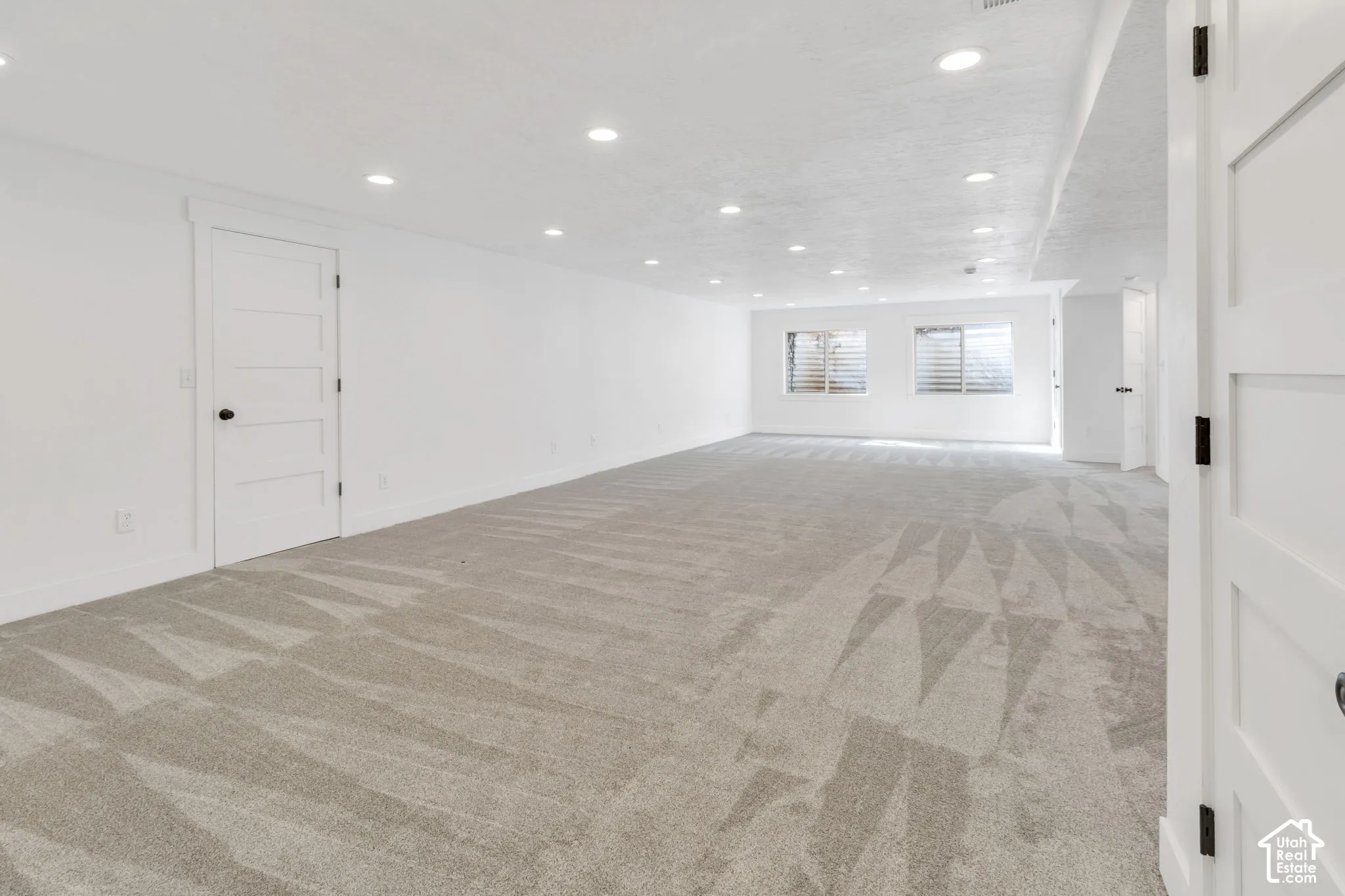 Expansive room with neutral carpeting, recessed lighting, and white walls