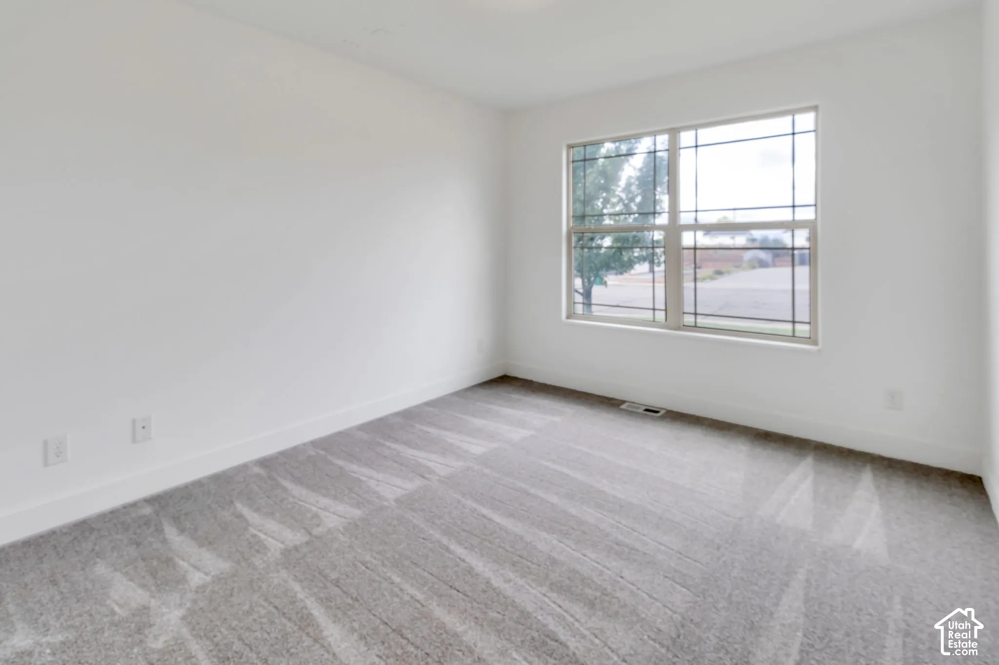 Bright corner bedroom featuring expansive windows with natural light, neutral wall finishes, and plush carpeting throughout