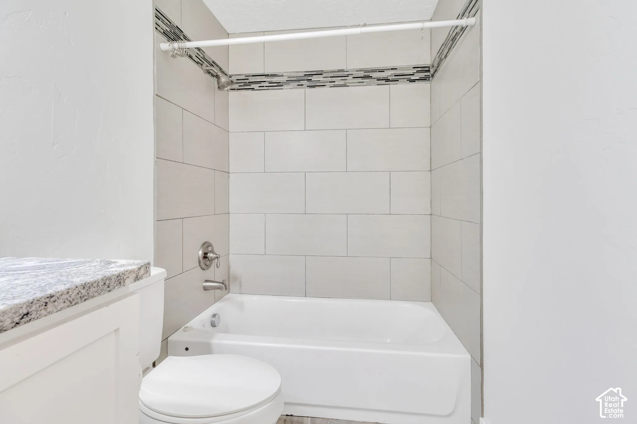 White subway tile surround with a decorative accent band, complete with a chrome shower fixture