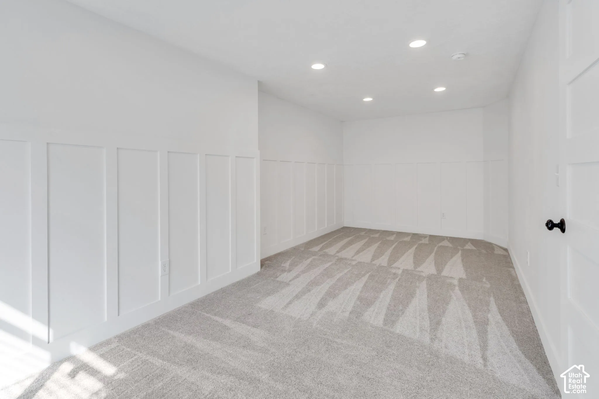 Board and batten wainscoting, recessed lighting, and light-toned carpeting