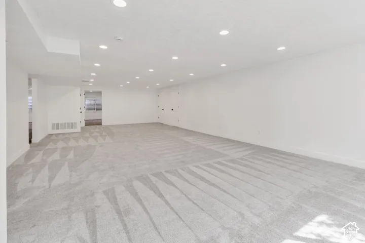 Expansive room featuring light gray carpet, recessed lighting, and white painted walls