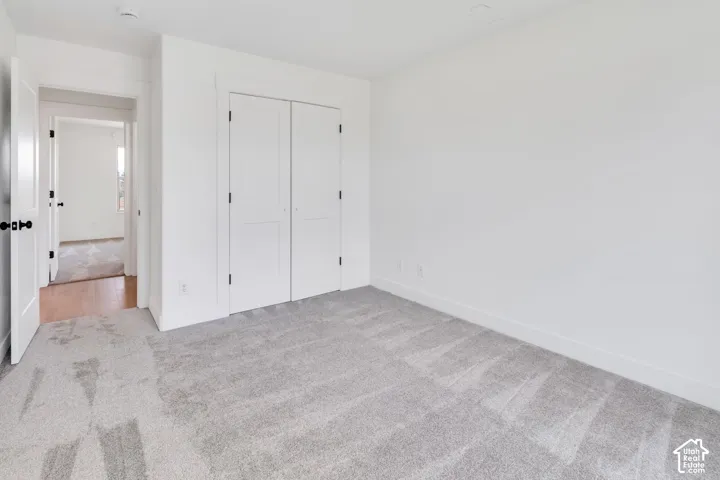 White walls, light gray carpet, and white bi-fold closet doors