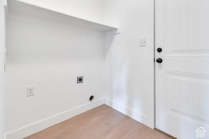 Integrated laundry connections with an overhead shelf and light wood-finish flooring