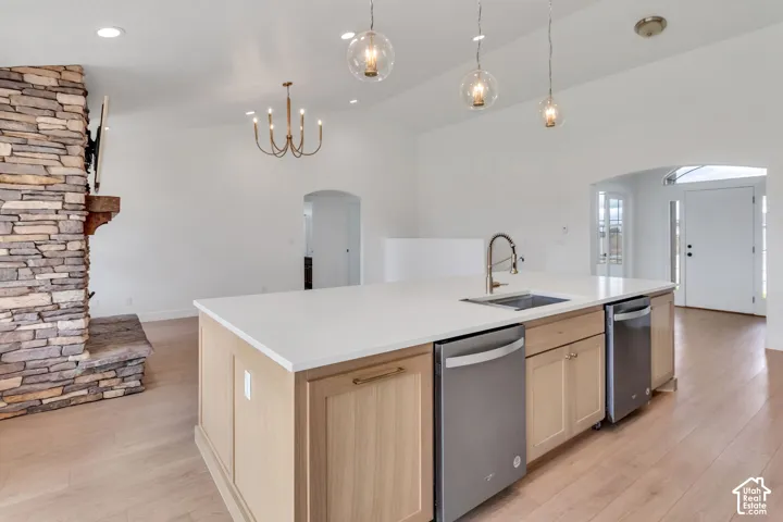 Open-concept living area featuring a stone fireplace, wood-finish flooring, and a kitchen island with built-in appliances
