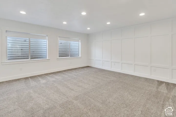 Recessed lighting, light gray carpet, window treatments, white wainscoting, and white trim