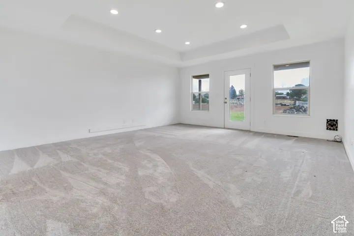 Recessed lighting illuminates a tray ceiling and light-toned carpeting