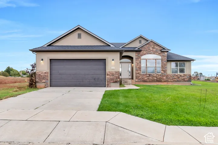 Stucco and stone exterior with an attached garage, arched entryway, and a prominent front lawn