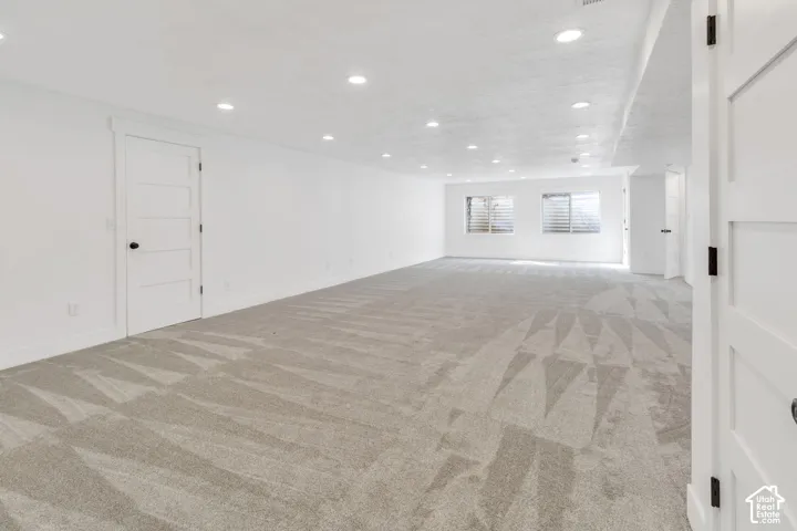 Expansive room with neutral carpeting, recessed lighting, and white walls